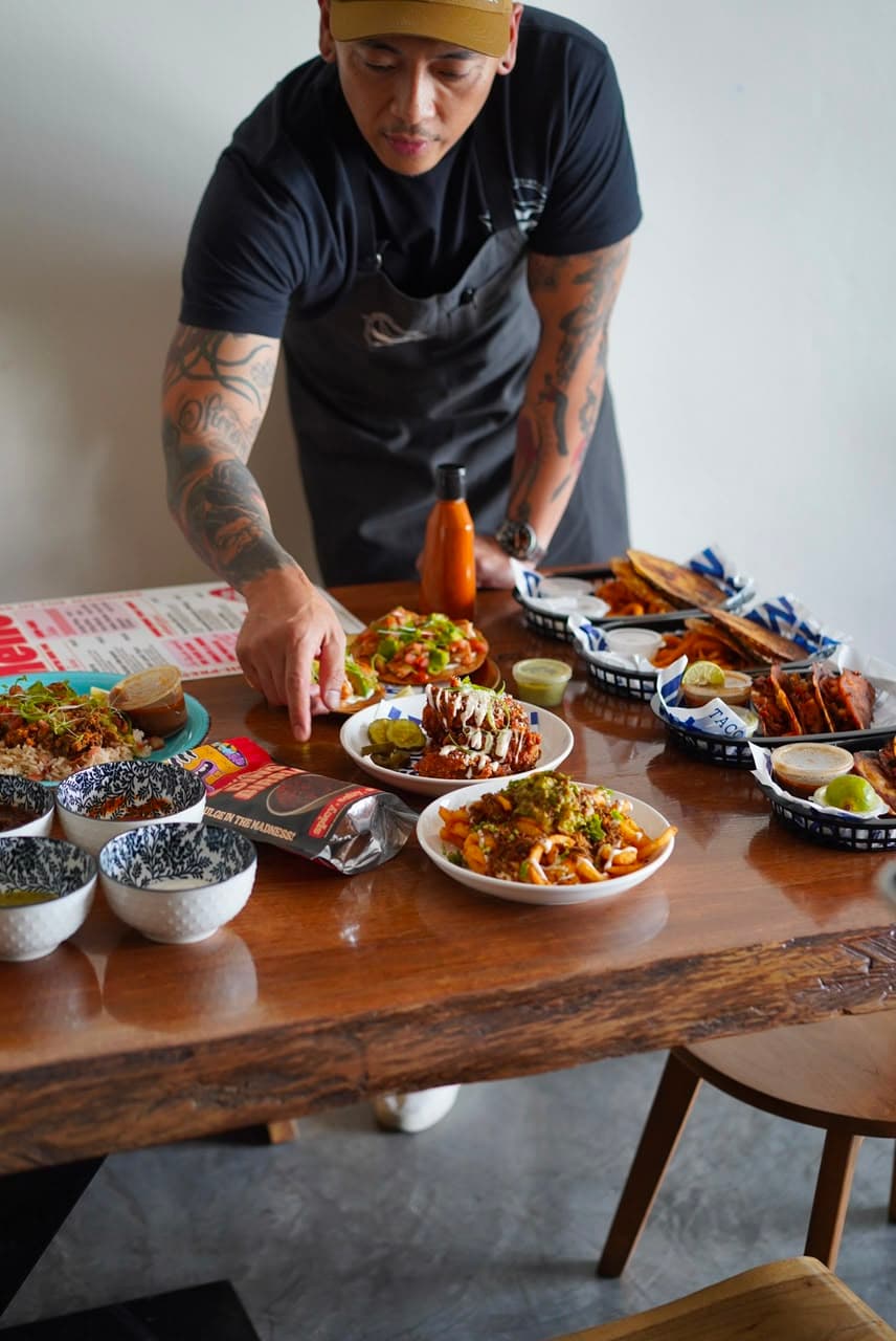 Chef Effardy laying out a full Taco Madness spread of tacos, tostadas, wings and fries